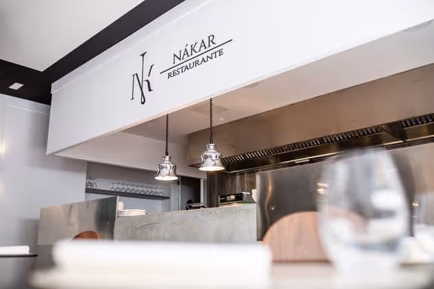Cocina abierta vista desde la sala, con el logotipo de Nákar sobre el pase